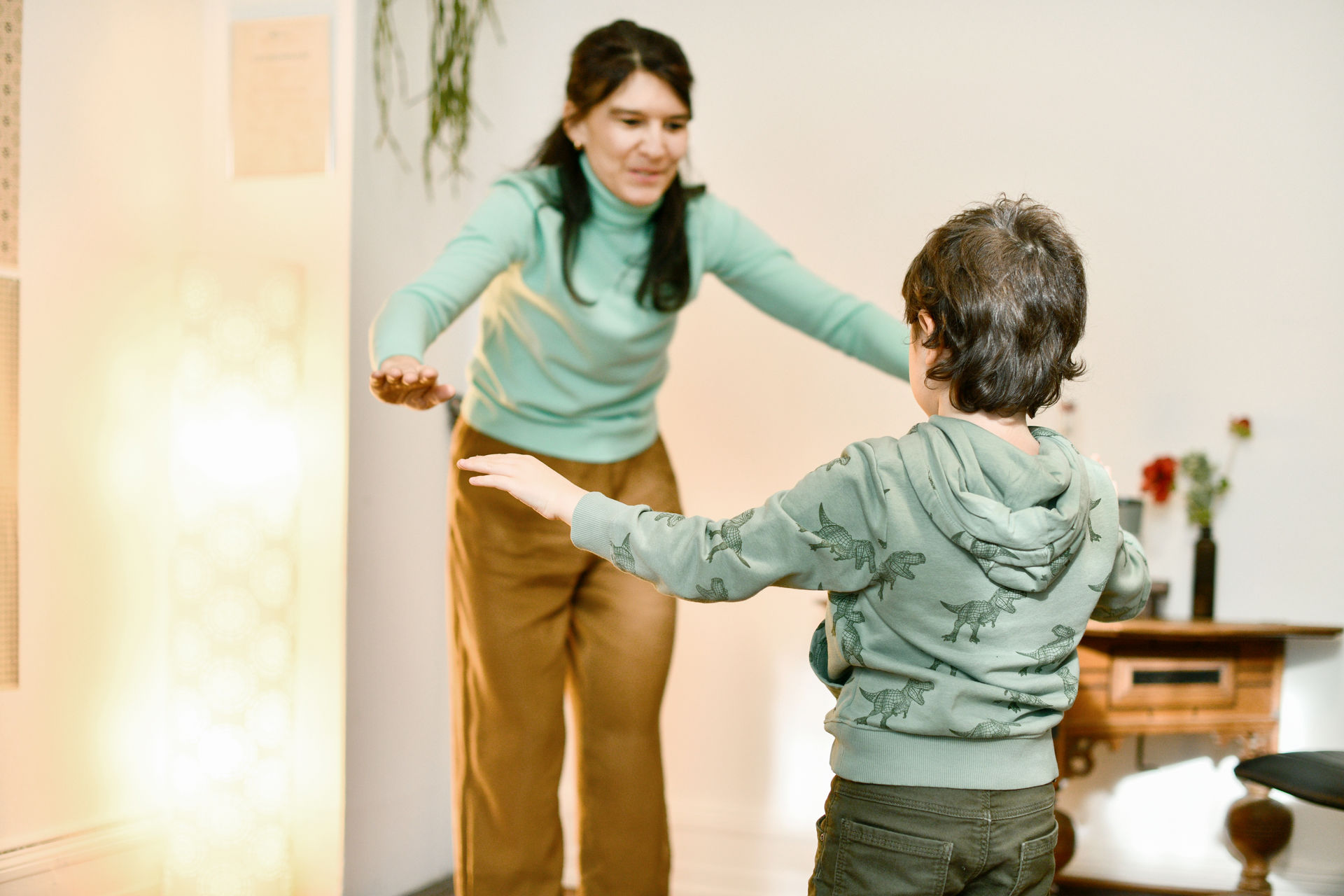 Therapiesituation mit einem Kind. Pascale Hauser und das Kind machen beide die gleichen Armbewegungen.