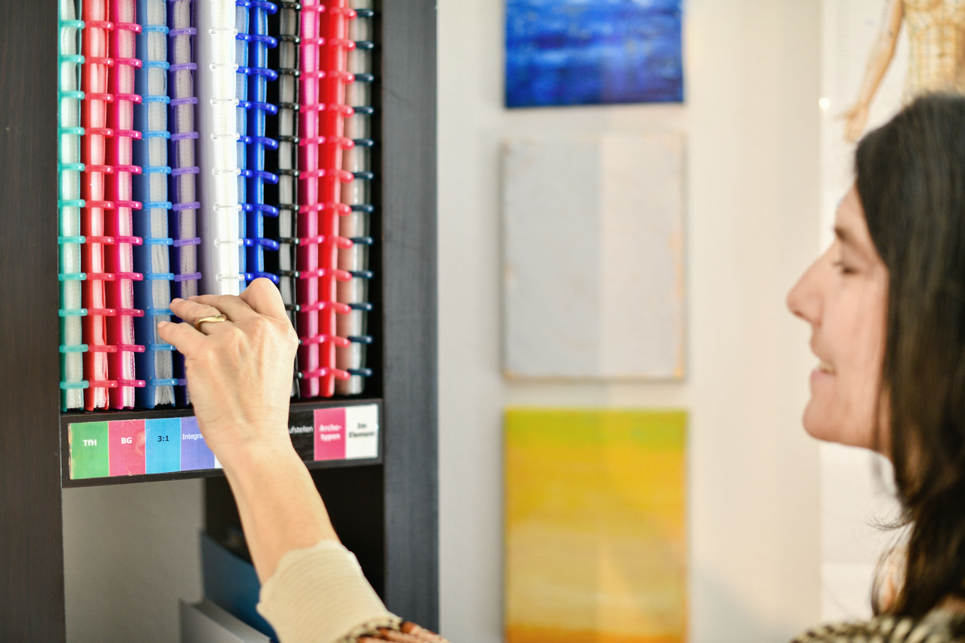 Detailansicht eines der Regals in der Praxis für Kinesiologie in Winterthur. Man erkennt, wie Pascale Hauser einen der Ordner nimmt.