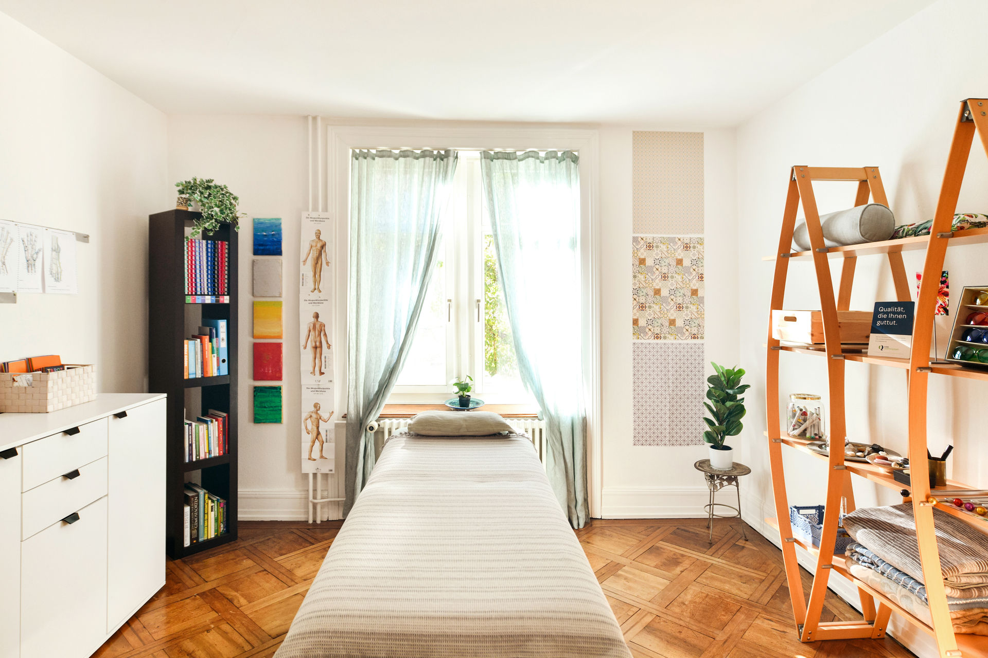 Übersicht des Praxisraumes von Pascale Hauser. Ein heller, gemütlicher Raum mit Patientenliege und verschiedenen Regalen.